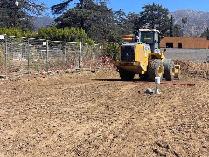 Wheel loader on a freshly graded building pad with a sand-cone density test apparatus set up on the compacted soil